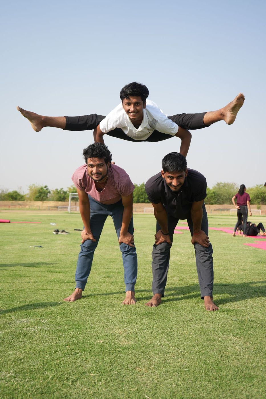Navpratap balancing in a straddle pose on the backs of two partners